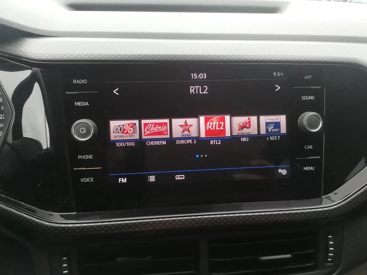 Vue rapprochée de l’écran tactile 8 pouces du Volkswagen T-Cross blanc affichant les stations radio FM.