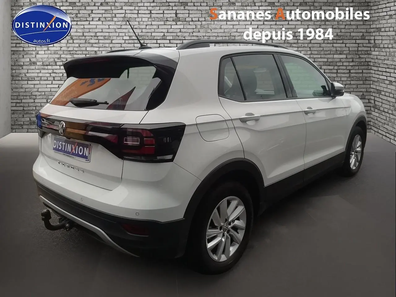 Vue 3/4 arrière droite d'un Volkswagen T-Cross blanc 2020 avec attelage et feux arrière foncés.