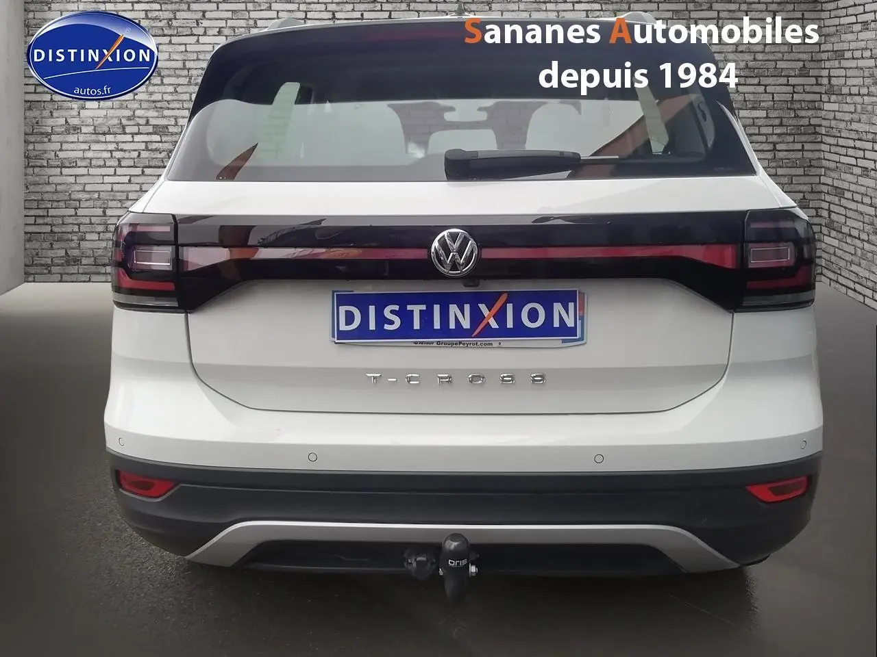 Vue arrière d'un Volkswagen T-Cross blanc avec feux arrière noirs et attelage de remorque visible.