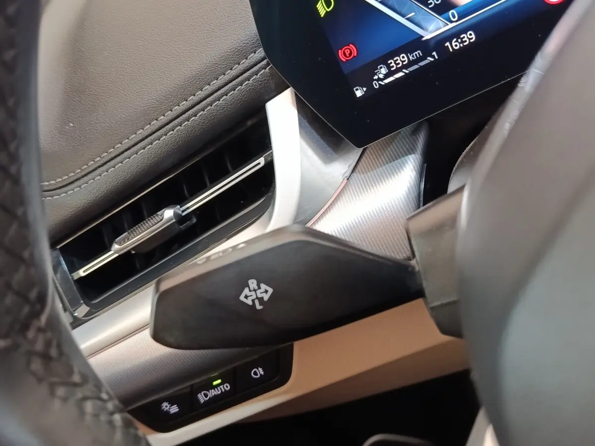 Détail intérieur du BMW X1 xDrive25e 2024 montrant le commodo de clignotant côté gauche et partie du tableau de bord gris foncé.