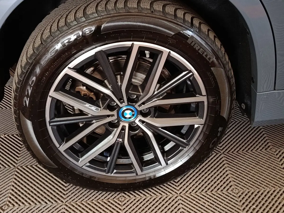 Gros plan sur la jante alliage noire et argentée avec logo BMW d’un BMW X1 xDrive25e gris foncé.
