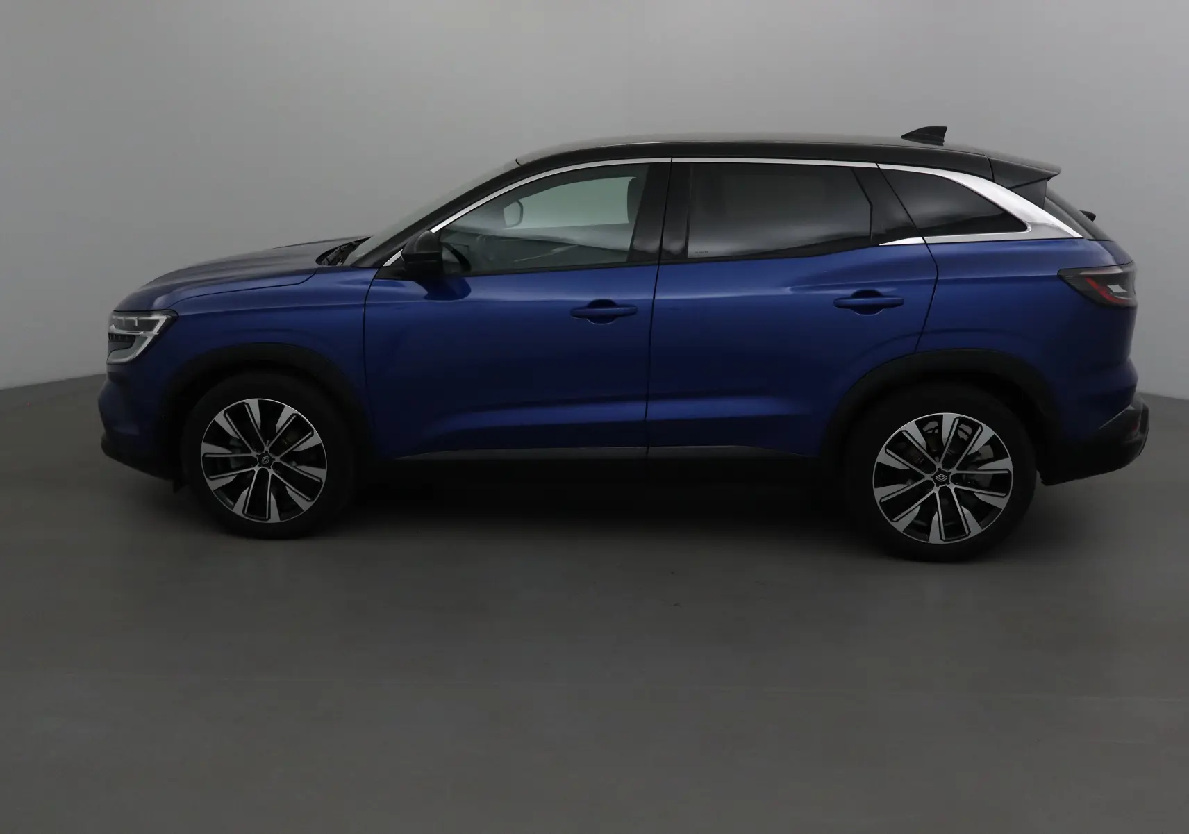 Profil côté gauche du Renault Austral 2023 bleu Iron avec toit noir et jantes alliage 19 pouces.