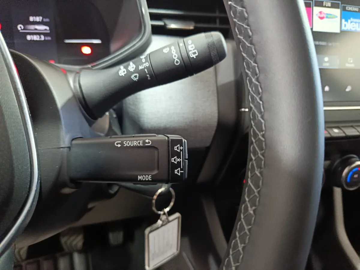 Gros plan sur les commandes au volant en cuir noir de la Renault Clio gris foncé Evolution Blue dCi 100 2025.