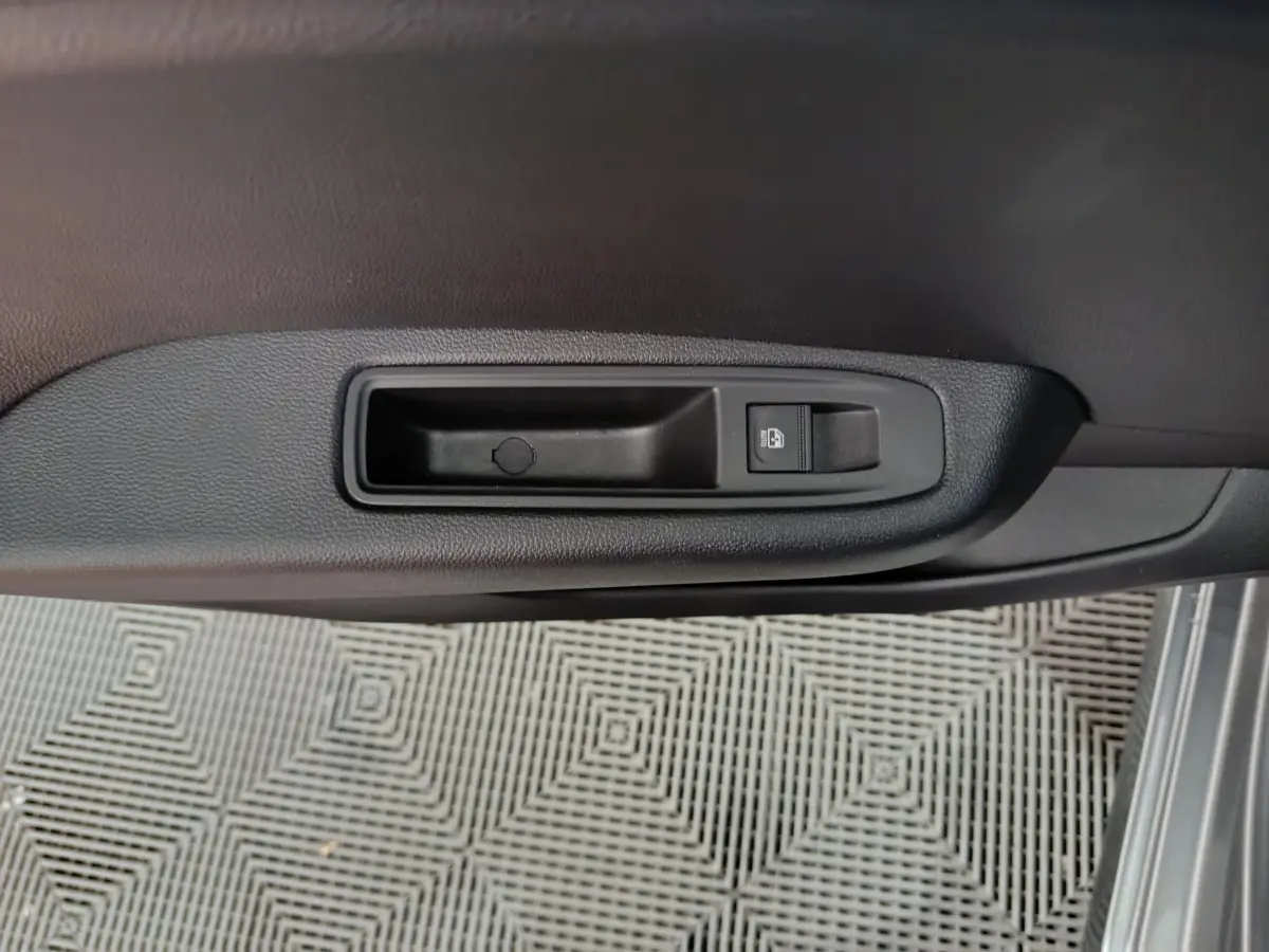 Bouton de verrouillage des portes sur la portière côté droit d'une Renault Clio gris foncé, vue intérieure rapprochée.