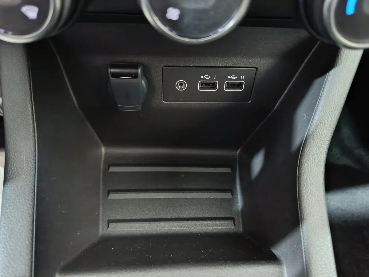 Vue rapprochée de la console centrale noire d'une Renault Clio 2025, montrant deux ports USB et une prise auxiliaire.