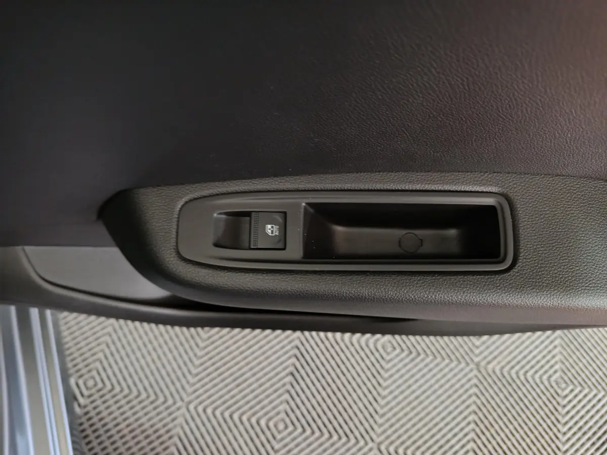 Bouton de commande de lève-vitre sur la porte intérieure côté conducteur d'une Renault Clio gris foncé 2025.