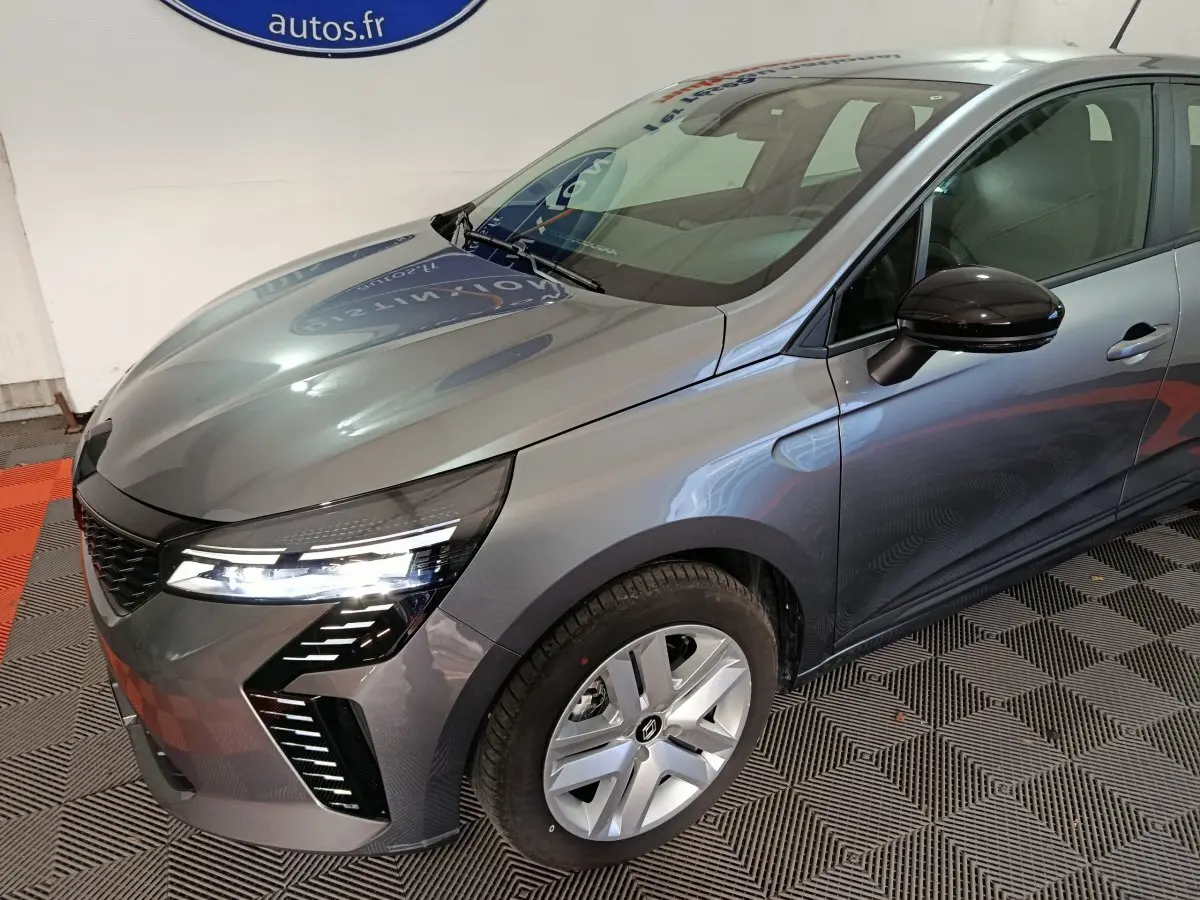 Vue 3/4 avant droit d'une Renault Clio gris foncé avec phares LED et rétroviseurs noirs brillants.