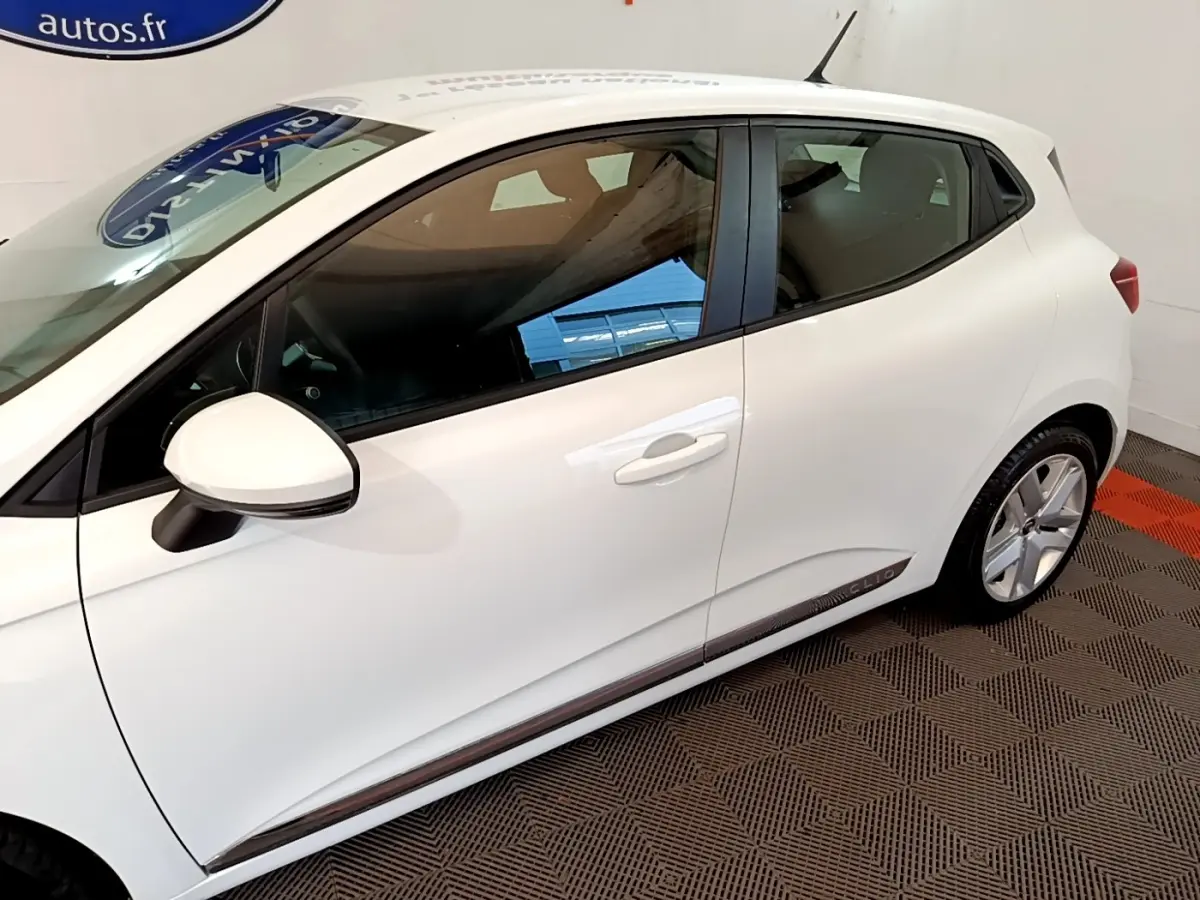 Vue latérale côté gauche d'une Renault Clio blanche Business Blue dCi 115 avec jantes alliage et rétroviseur blanc.