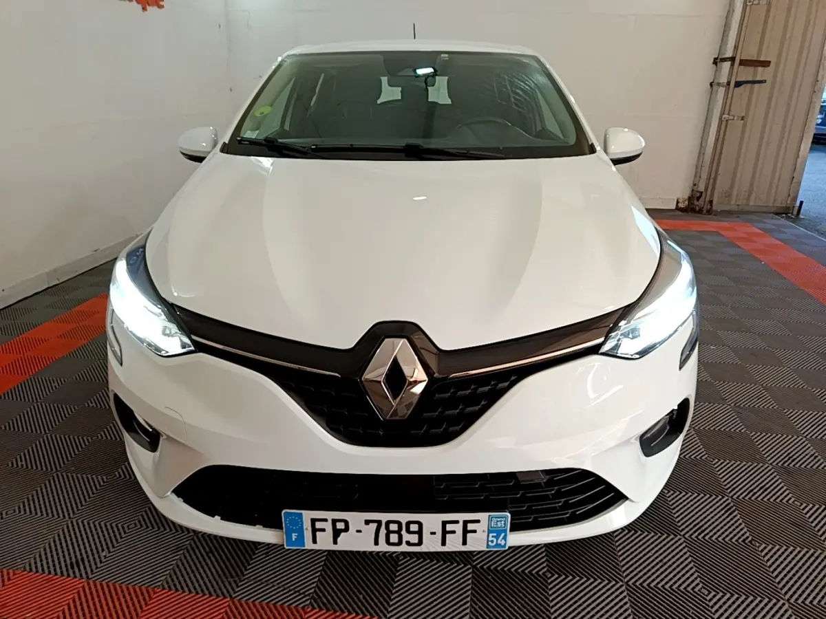 Vue avant d'une Renault Clio Business Blue dCi 115 blanche avec phares LED allumés dans un garage.