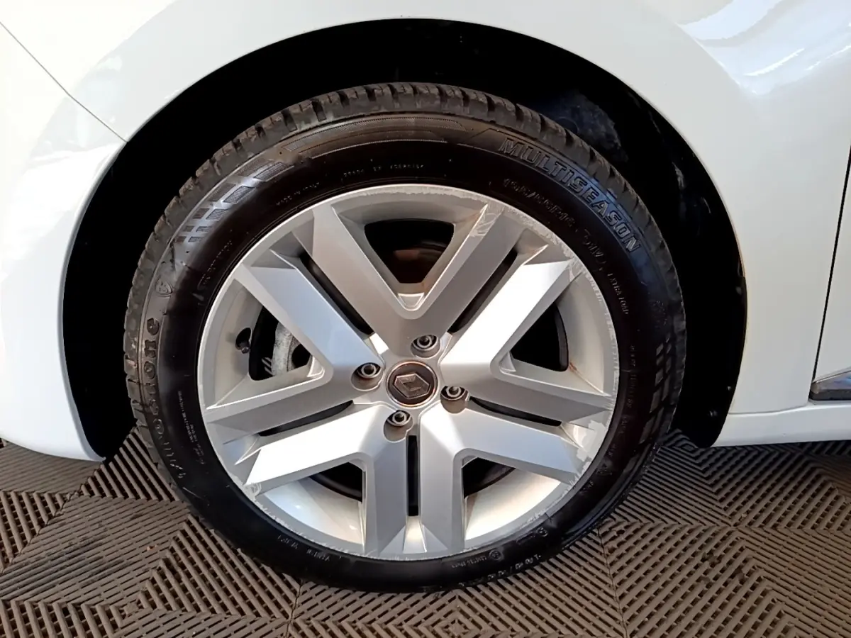 Gros plan sur la roue avant droite de la Renault Clio Business Blue dCi 115 blanche, avec jante alliage et pneu Multiseason.