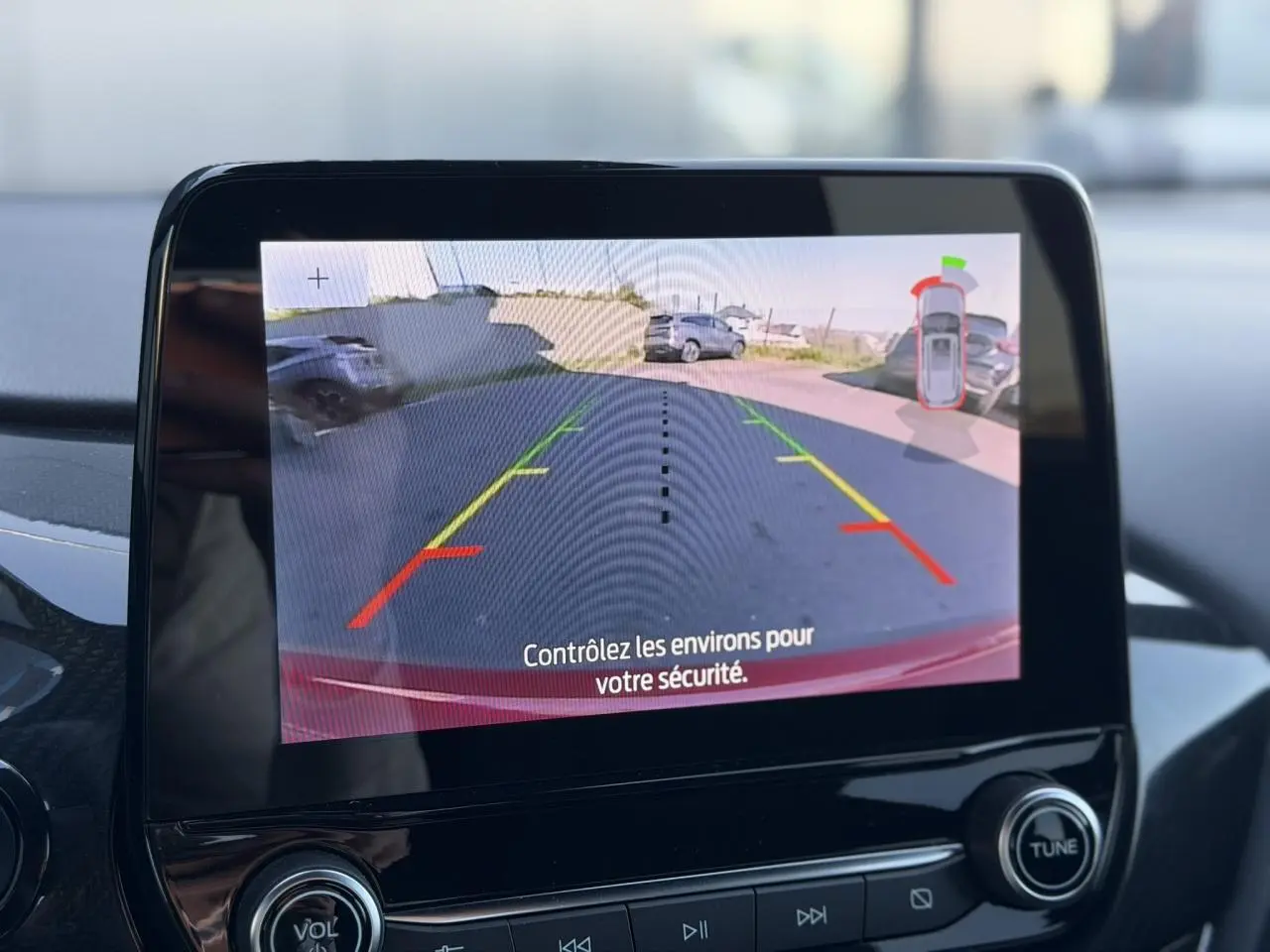 Écran tactile intérieur montrant la caméra de recul 180° du Ford Puma rouge, avec lignes d’aide au stationnement.
