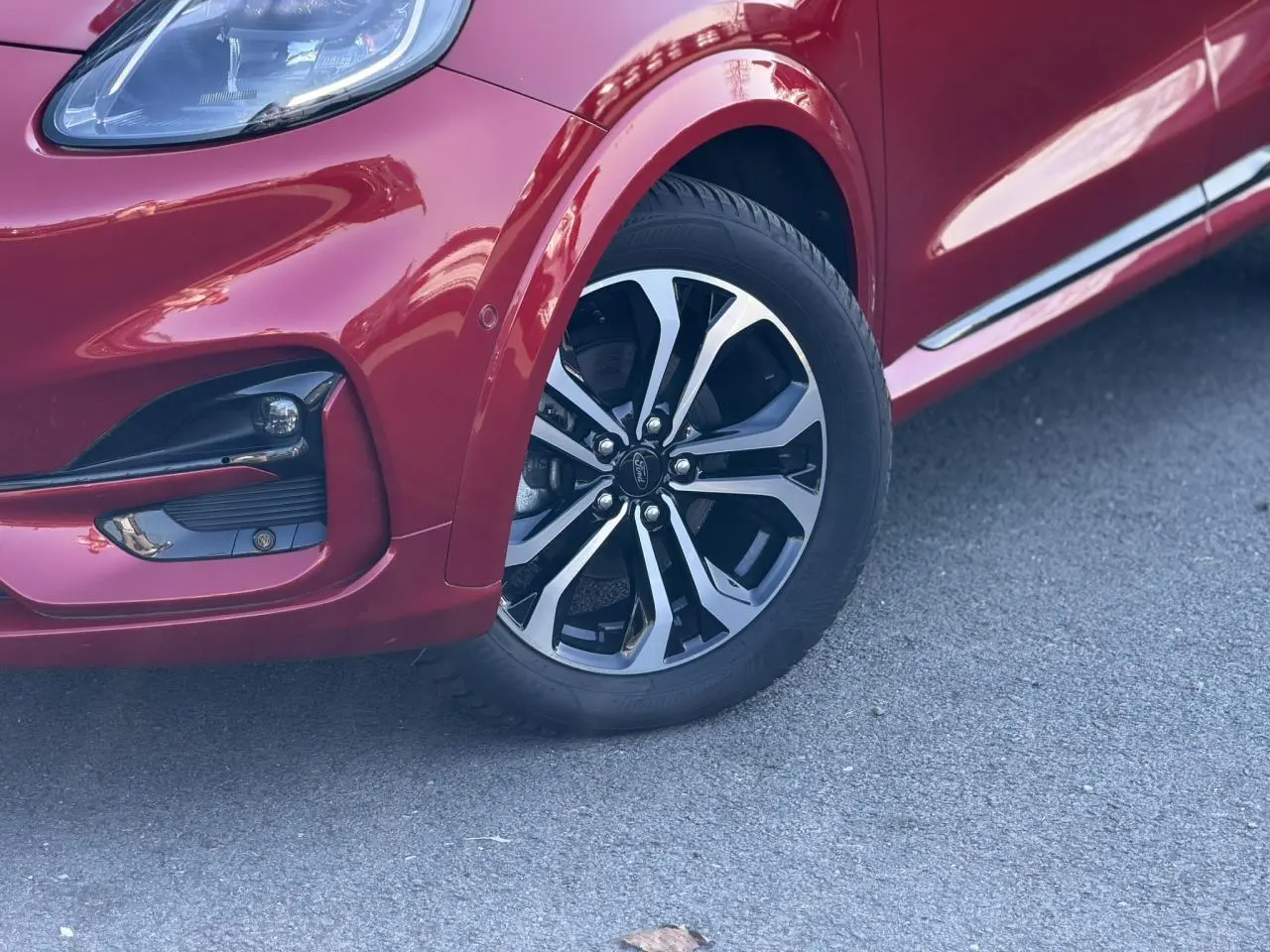 Gros plan sur la roue avant droite et le pare-chocs d’un Ford Puma rouge Fantastic avec jante alliage diamantée.