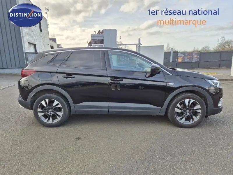 Profil droit d'un Opel Grandland X noir diamant, avec jantes alliage et vitres arrière surteintées, stationné en extérieur.