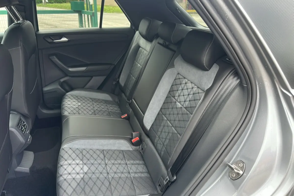 Vue intérieure arrière droite du Volkswagen T-Roc gris pyrite, montrant la banquette arrière en tissu avec motifs géométriques.