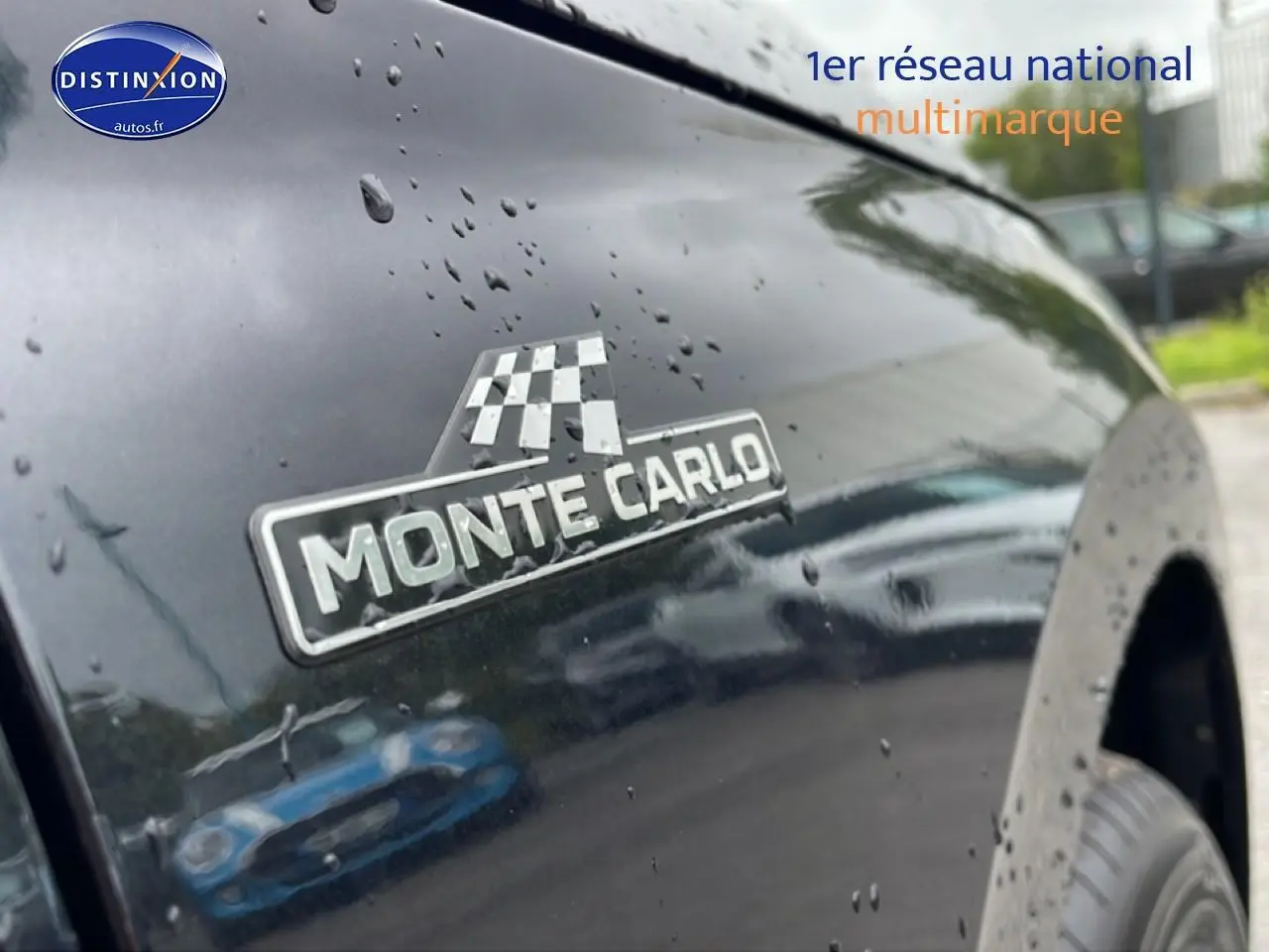 Gros plan sur l'écusson Monte Carlo sur l'aile avant droite d'un Skoda Kamiq noir brillant avec gouttes de pluie.