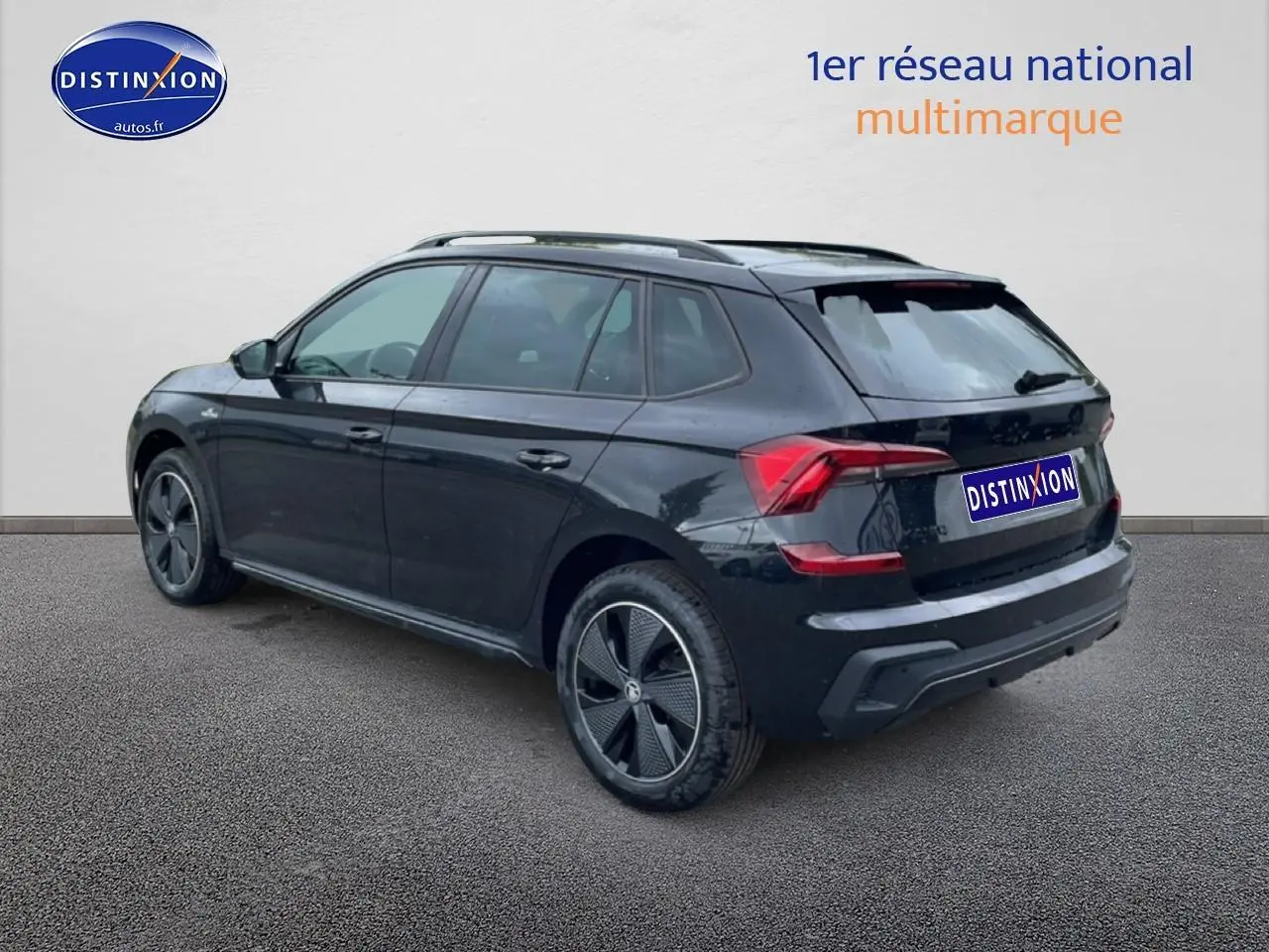SKODA KAMIQ noir vue 3/4 arrière droit, jantes alu noires et barres de toit visibles sur fond clair.