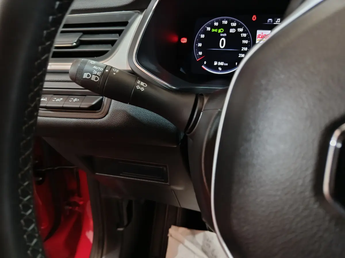 Détail du combiné d'instruments numérique et commandes d'éclairage côté gauche du volant d'un Renault Captur rouge 2024.