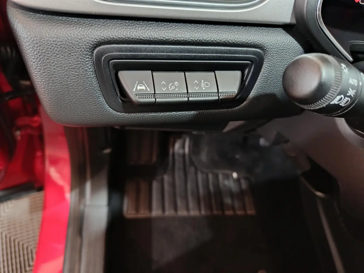 Gros plan sur les commandes d'assistance à la conduite du tableau de bord côté gauche d'un Renault Captur rouge 2024.
