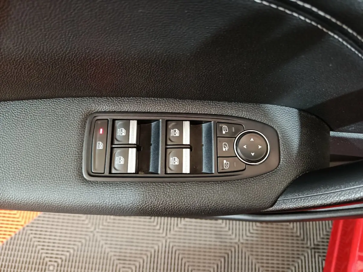 Commande des vitres électriques et réglage des rétroviseurs sur la porte côté conducteur d'un Renault Captur rouge 2024.