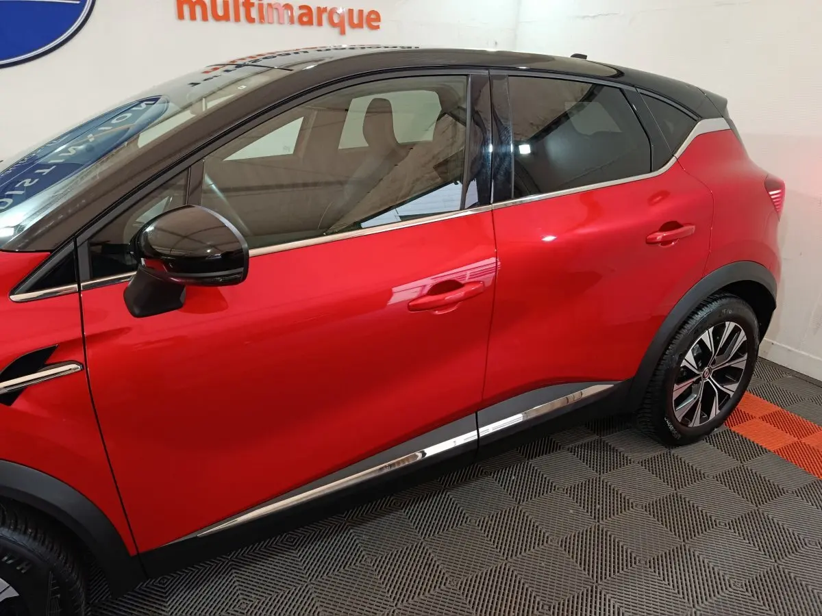 Profil côté gauche du Renault Captur rouge 2024 avec toit noir et jantes alliage bicolores.