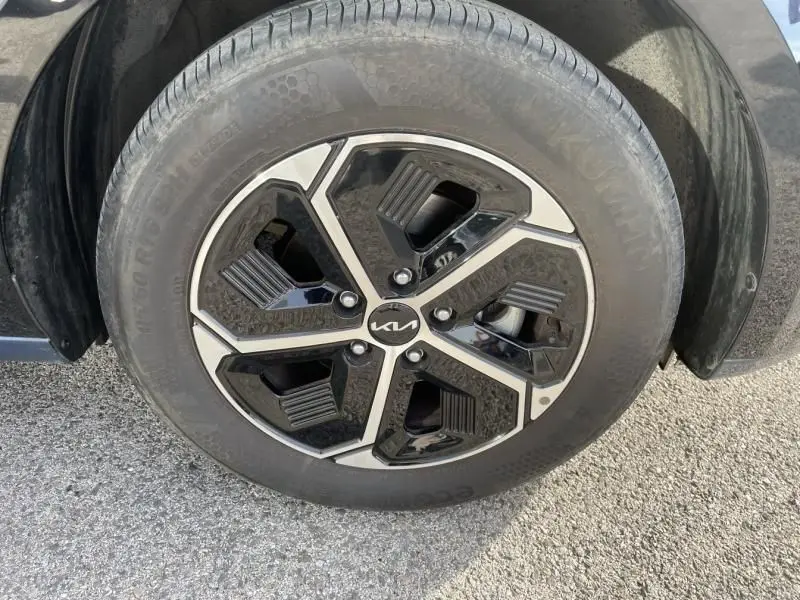 Gros plan sur la roue avant droite du KIA NIRO 2024 bleu métal, avec jante alliage noire et argentée au design moderne.