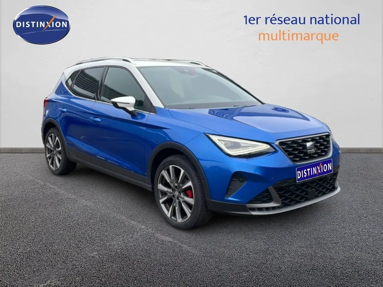 SEAT Arona bleu saphir métal avec toit blanc, vue 3/4 avant droit, jantes alliage et calandre noire distinctive.