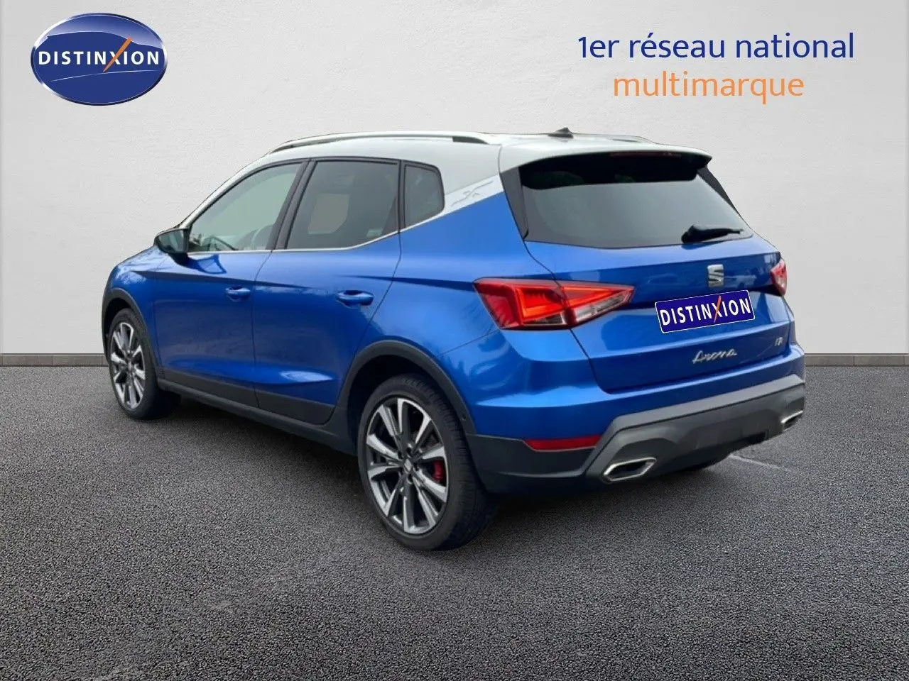 SEAT Arona 2025 bleu saphir métal avec toit blanc, vue 3/4 arrière côté gauche, jantes alliage et feux LED.