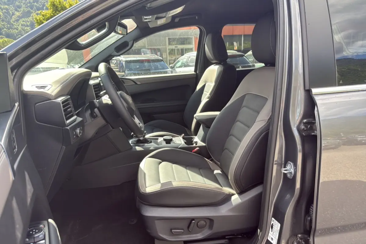 Vue intérieure côté conducteur du Volkswagen Amarok Simple Cabine 2026 gris foncé, sièges cuir et tableau de bord moderne.
