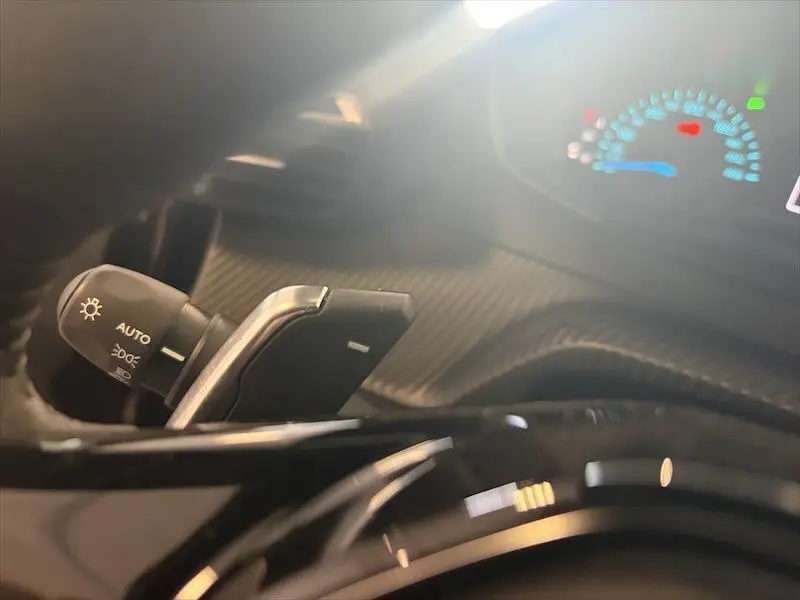 Gros plan sur la commande des feux et palette de changement de vitesse dans l’habitacle du Peugeot 2008 Hybrid noir métal.