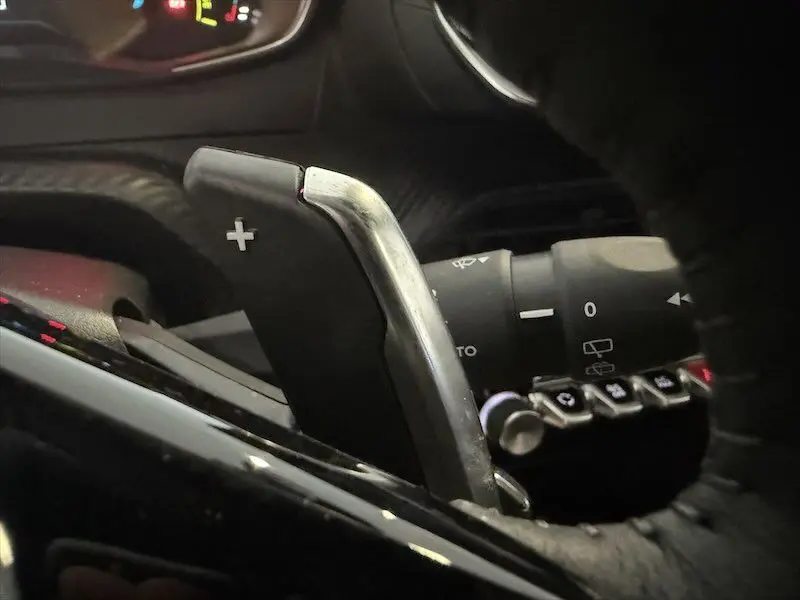 Gros plan sur la palette de changement de vitesse droite en aluminium brossé dans l’habitacle noir du Peugeot 2008 Hybrid 145ch.
