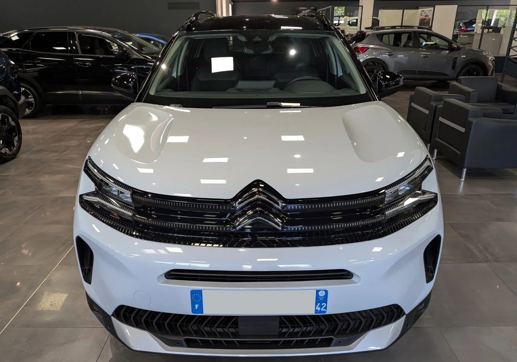 Vue avant d'un Citroën C5 Aircross 2025 blanc Okénite avec toit noir, calandre noire brillante et éclairage LED fin.