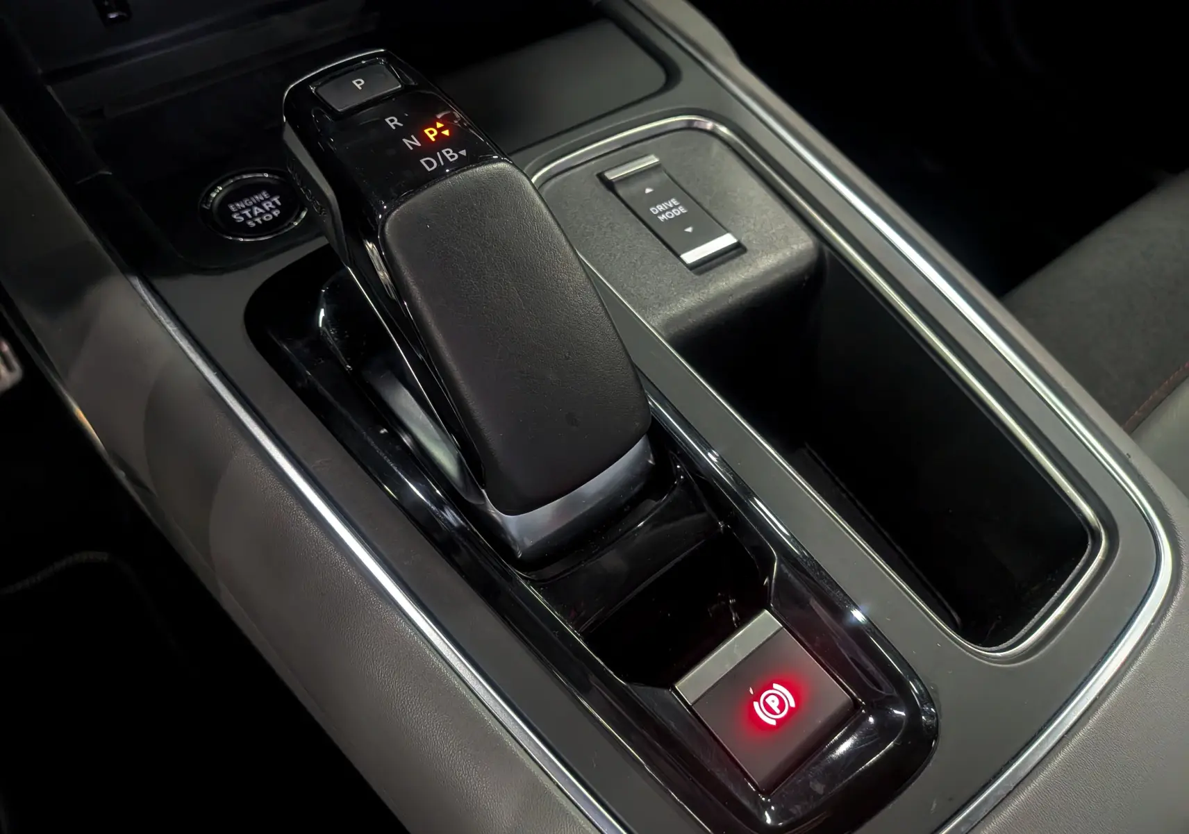 Gros plan sur la console centrale noire du Citroën C5 Aircross hybride rechargeable, avec levier de vitesses automatique et bouton frein à main électrique.