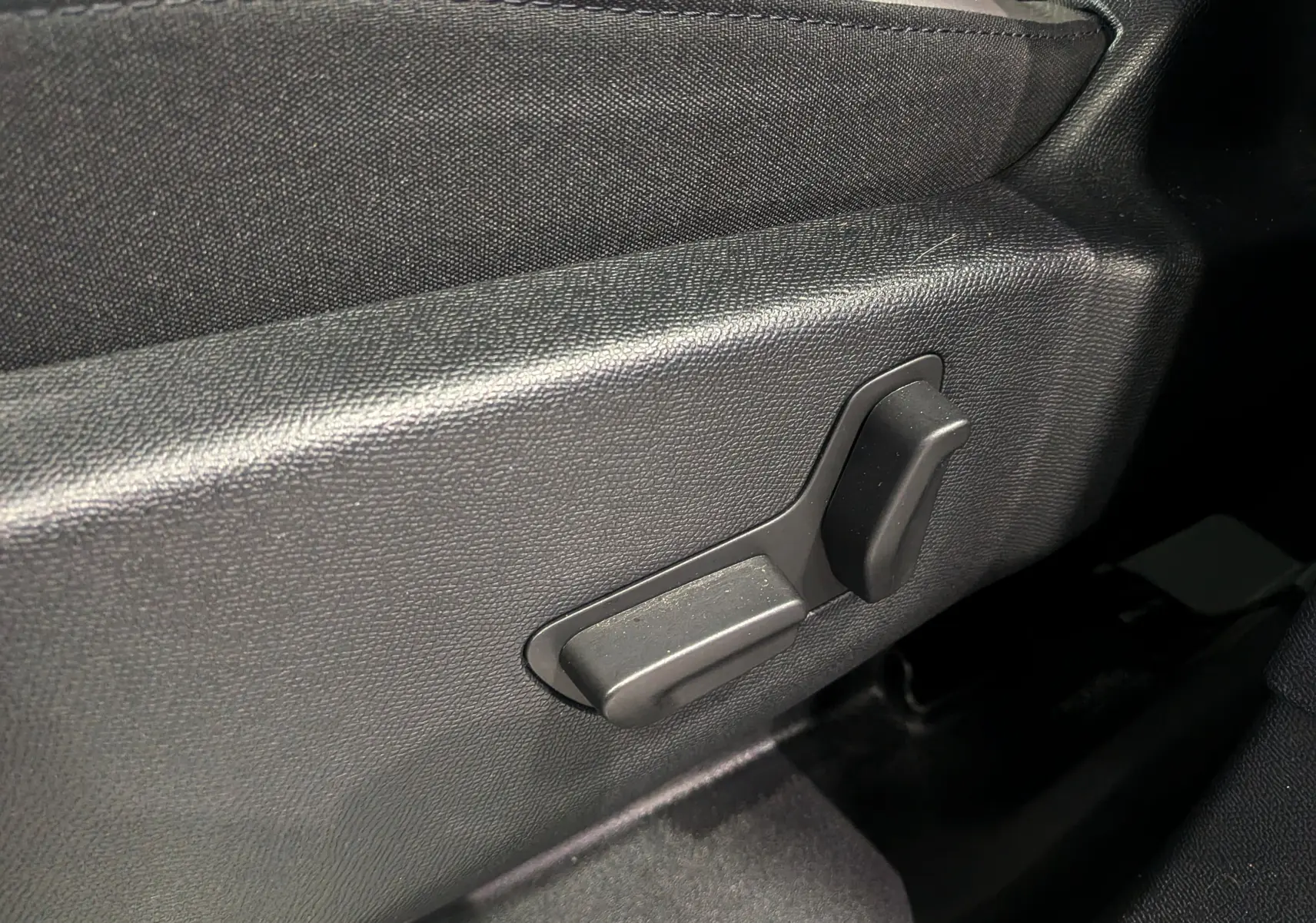 Gros plan sur les commandes électriques du siège conducteur du Citroën C5 Aircross hybride blanc, intérieur noir.