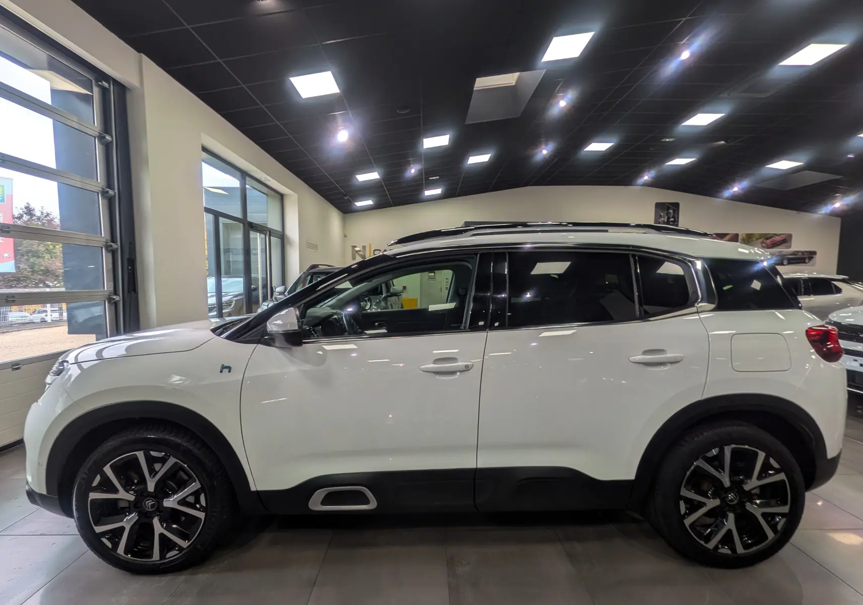 Profil côté gauche du Citroën C5 Aircross blanc glacier en hybride rechargeable, avec jantes noires et toit panoramique.