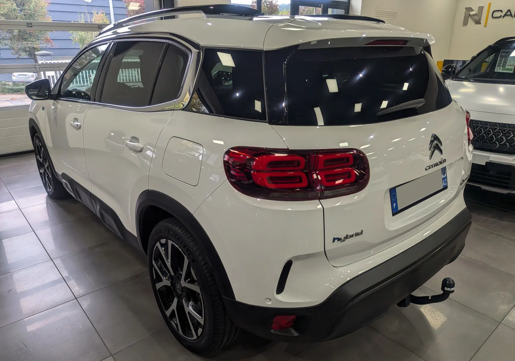 Vue 3/4 arrière droite d'un Citroën C5 Aircross blanc glacier hybride rechargeable avec feux arrière LED distinctifs.