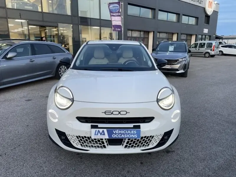 Vue de face d'une FIAT 600 blanche 2025 avec phares allumés et logo 600 visible sur la calandre.