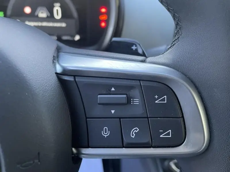 Gros plan sur les commandes au volant côté gauche du Fiat 600 blanc 2025, avec boutons de volume et téléphone.