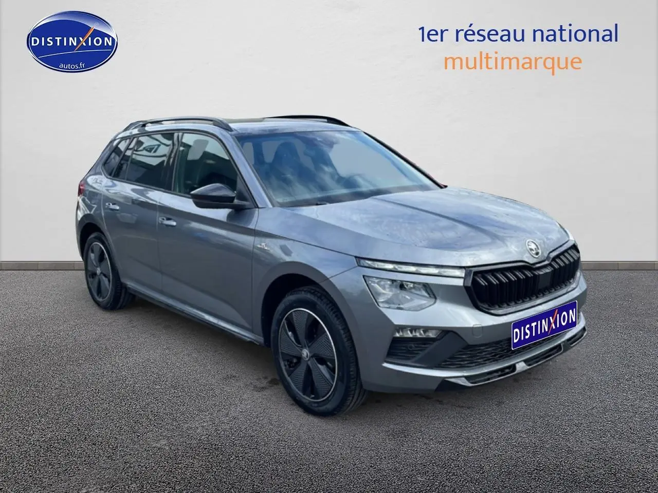 Vue 3/4 avant droite d'un Skoda Kamiq gris graphite avec jantes alu et barres de toit noires.