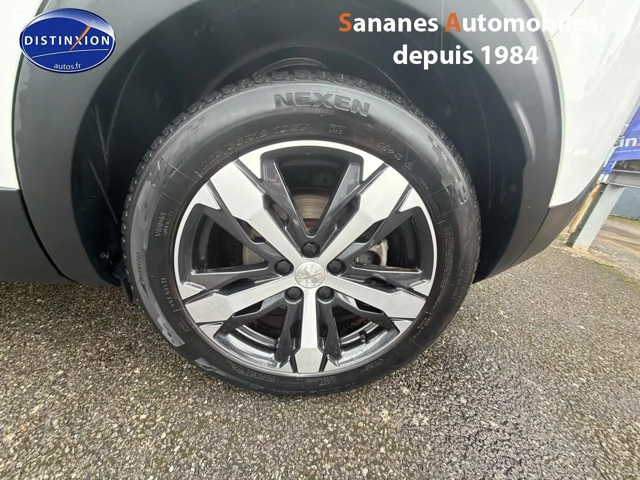 Gros plan sur la roue avant droite du Peugeot 3008 blanc nacré, mettant en valeur la jante alliage 18 pouces Los Angeles.