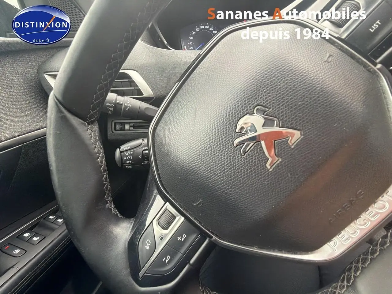 Gros plan sur le volant cuir noir avec logo Peugeot du Peugeot 3008 blanc, vue intérieure côté conducteur.