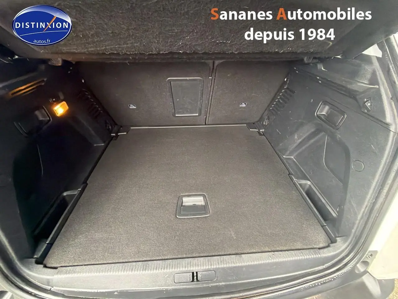 Coffre ouvert du Peugeot 3008 blanc nacré, vue intérieure montrant le plancher plat et les parois noires.