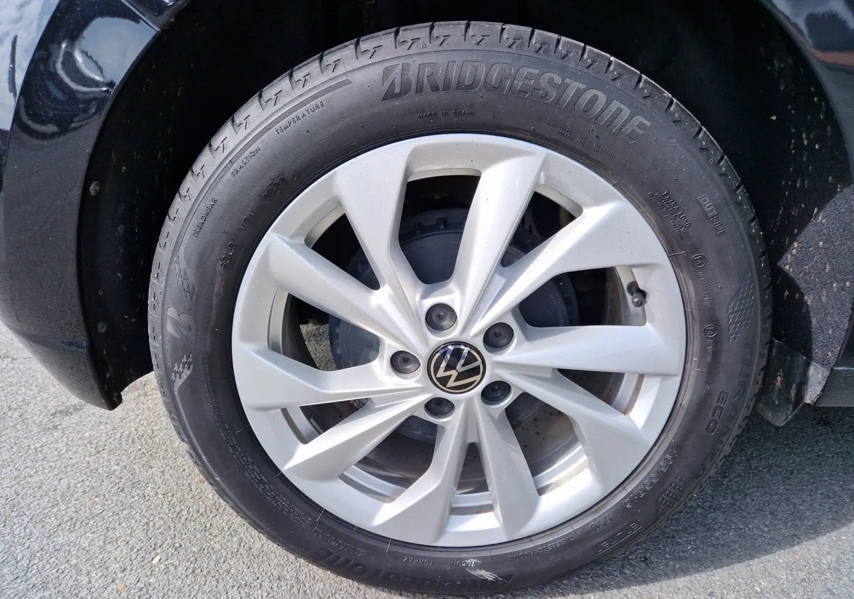 Gros plan sur la roue avant gauche d'une Volkswagen Polo noire avec jante argentée et pneu Bridgestone.