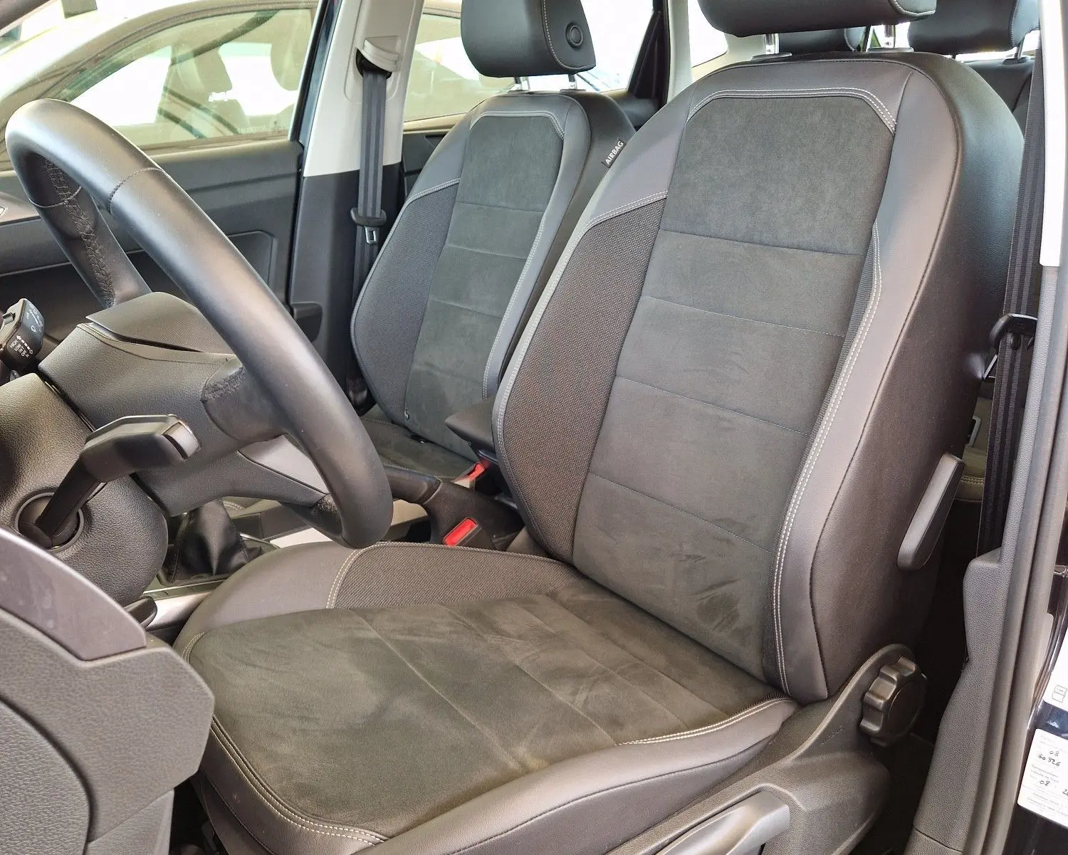 Vue intérieure côté conducteur d'une Volkswagen Polo noire 2022, sièges en tissu et cuir noir avec toit ouvrant.