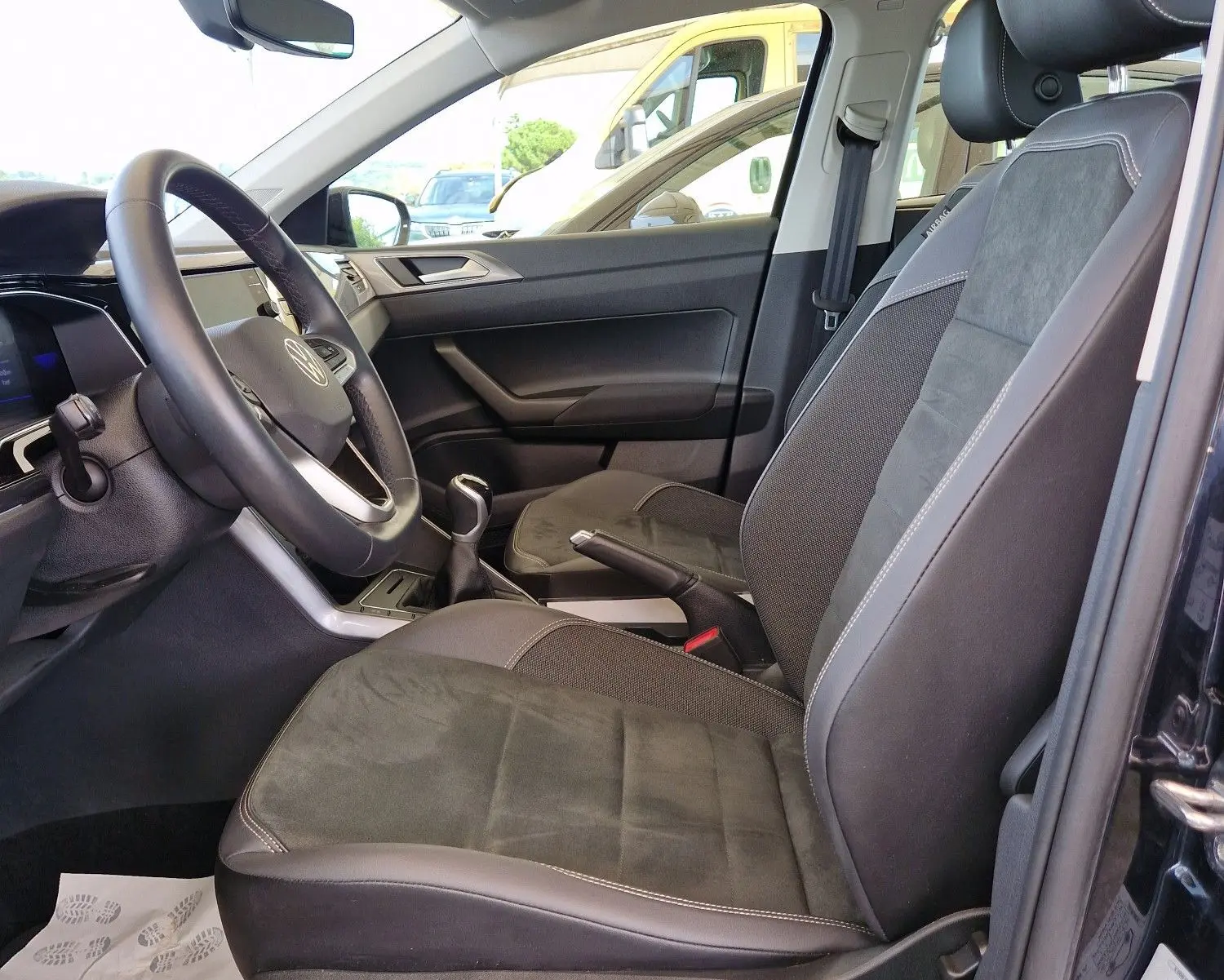 Intérieur côté conducteur de la Volkswagen Polo noire 2022, sièges en tissu et alcantara avec toit ouvrant panoramique visible.