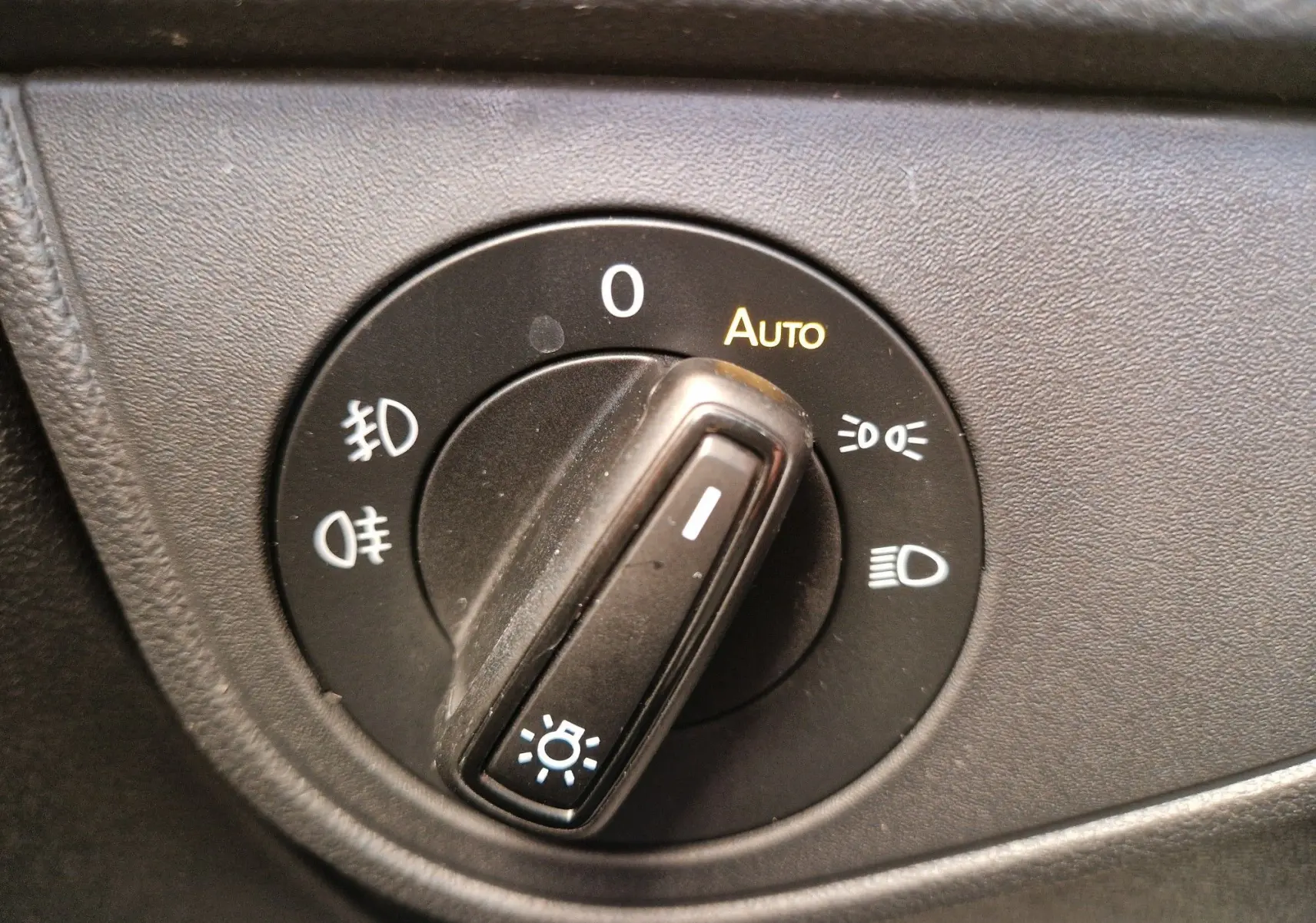 Gros plan sur le sélecteur de phares noir du tableau de bord d'une Volkswagen Polo 2022, avec mode automatique activé.