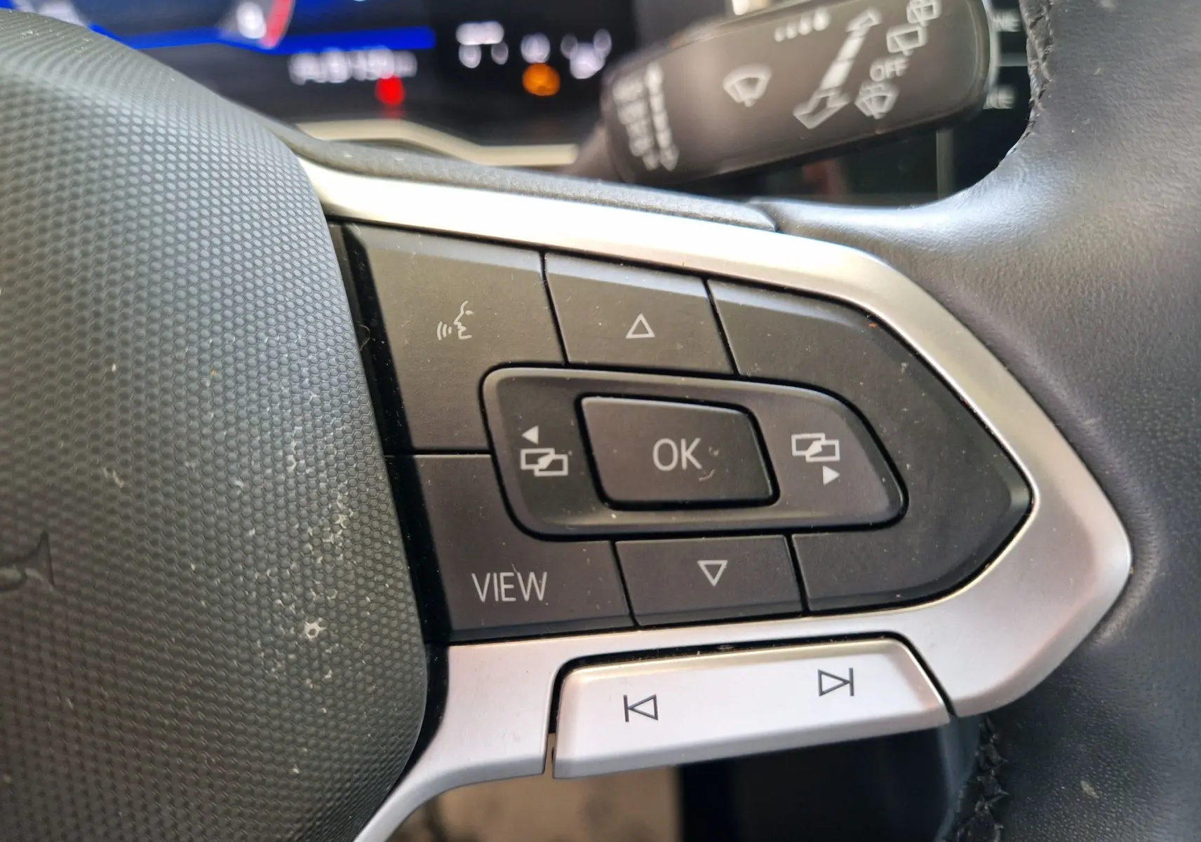 Gros plan sur les commandes au volant côté gauche de la Volkswagen Polo noire 2022 avec boutons multifonctions et affichage numérique.