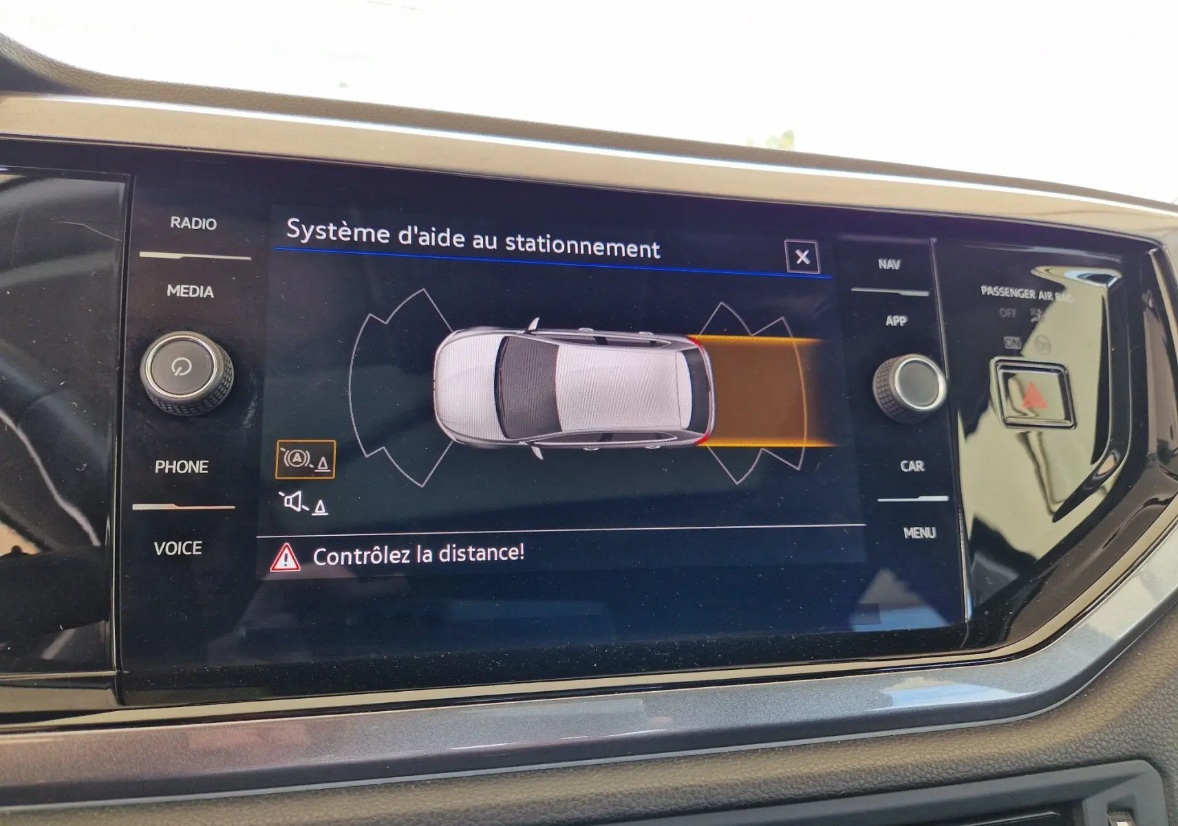 Écran tactile du système d'aide au stationnement dans une Volkswagen Polo noire, affichant l'alerte de distance.