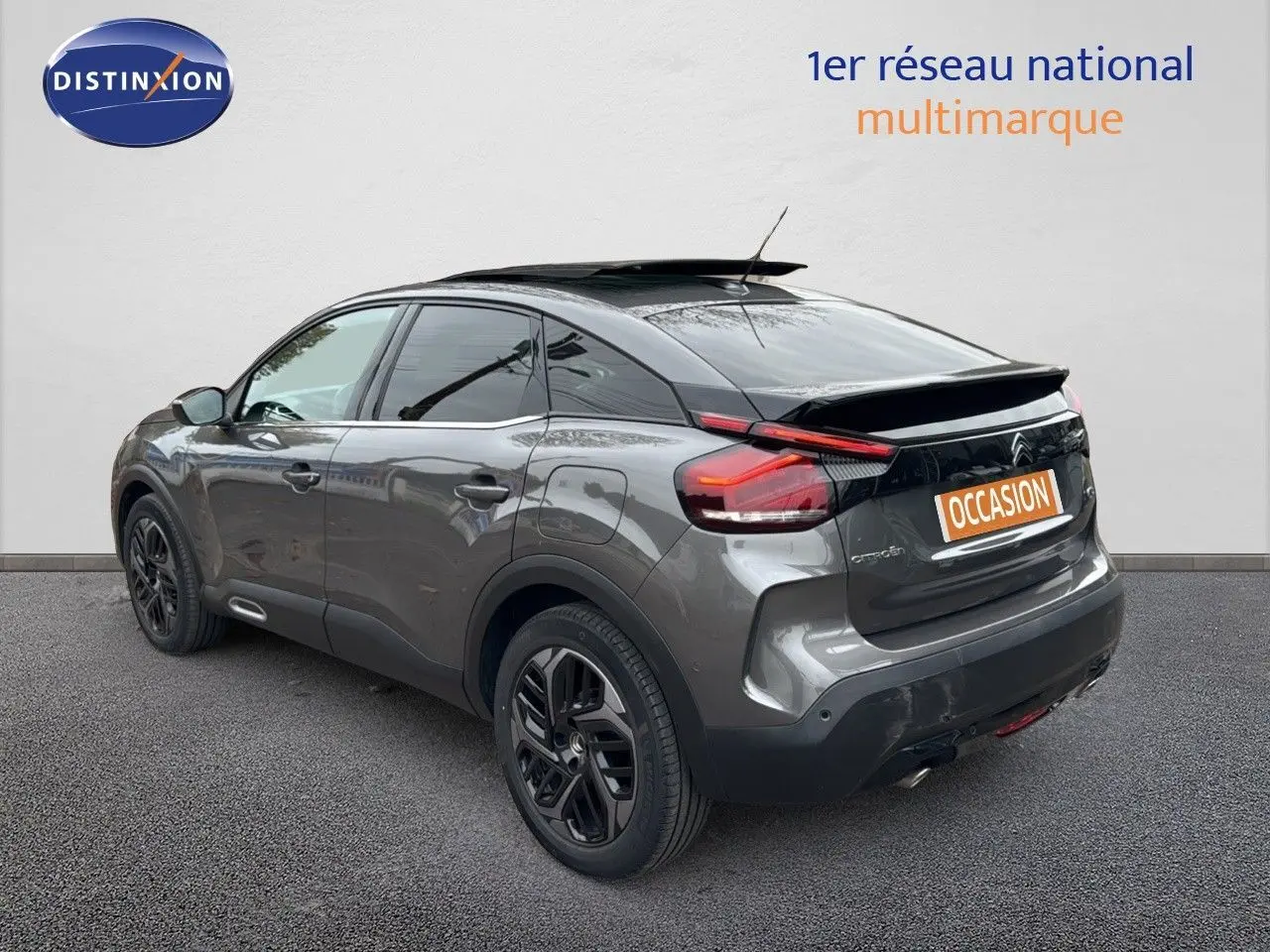 Citroën C4 gris avec toit noir en 3/4 arrière droit, mettant en valeur son design moderne et ses feux arrière distinctifs.