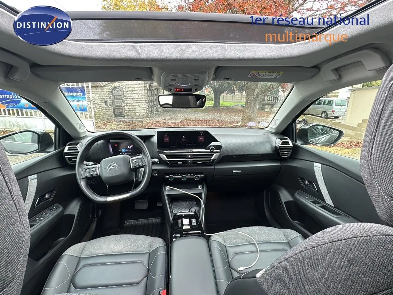 Intérieur moderne de la Citroën C4 PureTech 130ch, vue avant avec toit ouvrant et sellerie grise élégante.