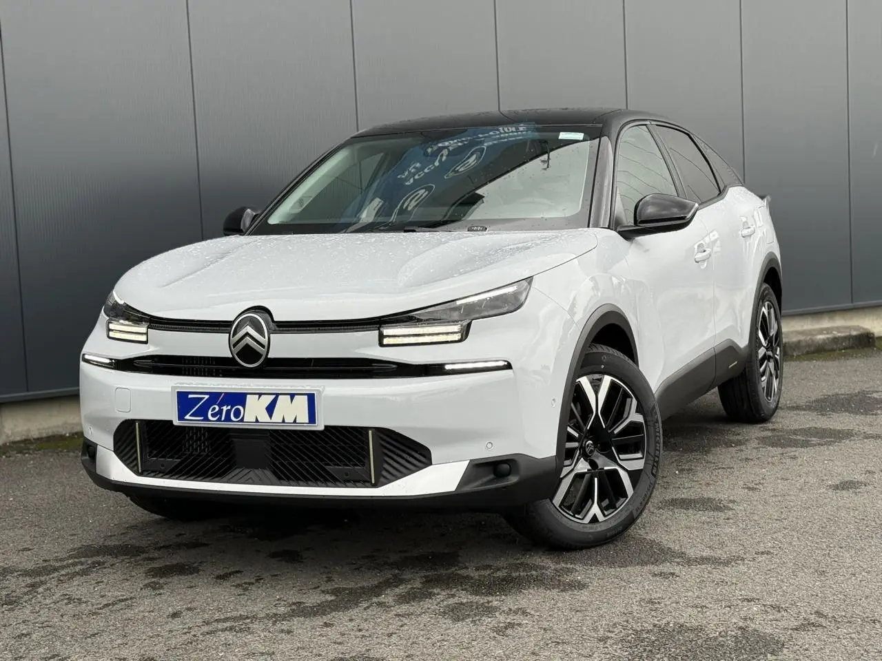 Citroën C4 NV Hybrid blanc Okénite avec toit noir, vue 3/4 avant mettant en valeur ses phares LED et jantes 18 pouces.